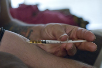 An intravenous drug user injecting heroin. Photo by Clay Duda.