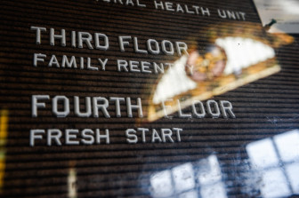 A hallway leading to the head office at the Family ReEntry Innovation Impact Center in Bridgeport, Conn., that is housed inside the First Baptist Church of Bridgeport. A sign at the front door of the Baptist church shows the reflection of the stained glass of the century old church. (Robert Stolarik for JJIE)