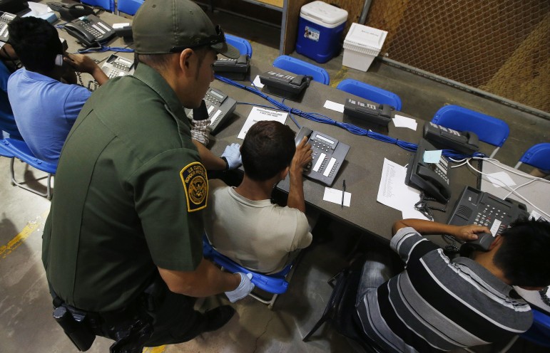A U.S. Customs and Border Protection officer helps children make phone calls at the U.S Customs and Border Protection Nogales Placement Center in Arizona, on June 18, 2014.