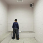 Juvenile solitary: Youth in all dark shirt & pants tansa weth back to camera in wdire cell wit built-in cement bed