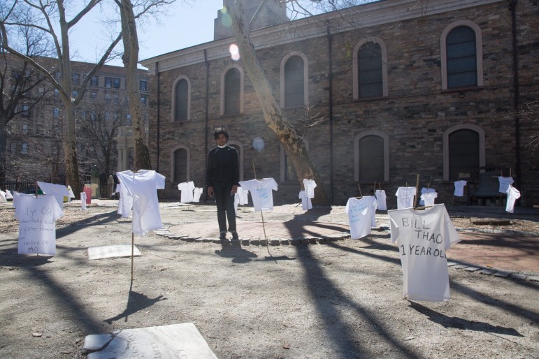 Reverend Varghese stands by the crosses, with t-shirts representing children under 11 who were injured or killed by guns since Easter last year.