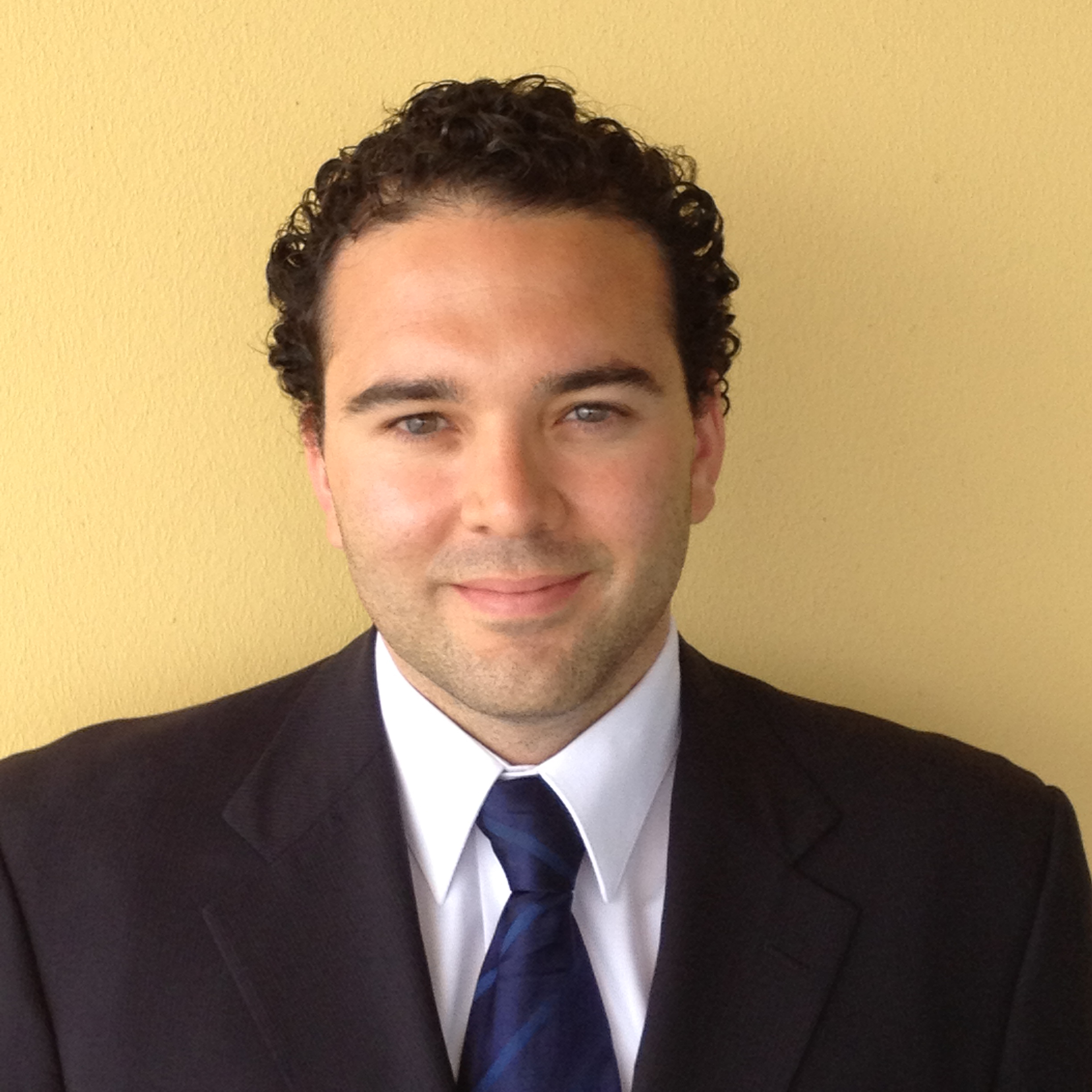actuarial tools: Michael Umpierre (headshot), smiling man with short dark curly hair, dark jacket, white shirt, dark blue striped tie