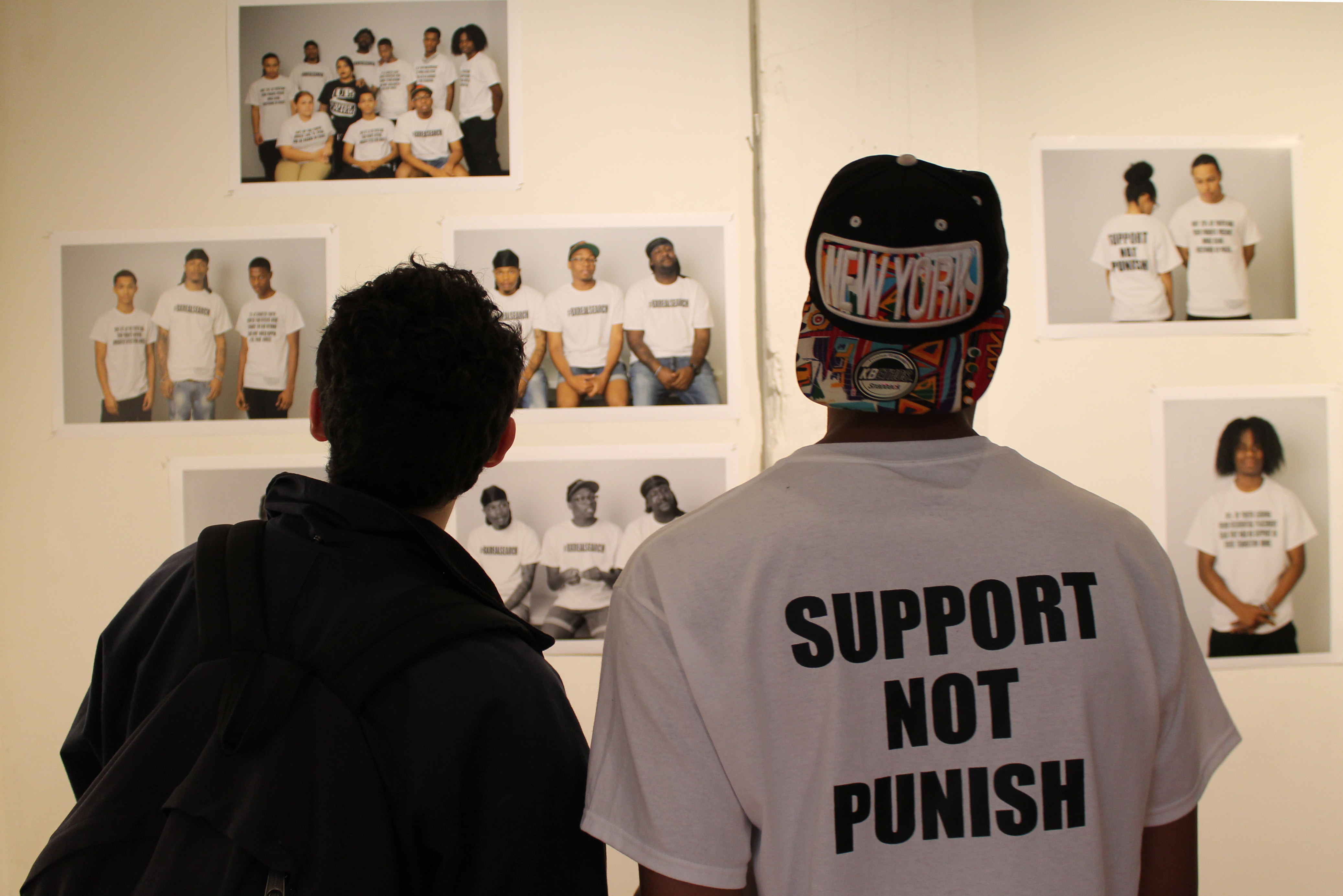DeVante Lewis (right) in front of portraits of local youth wearing shirts that highlight the report's main findings at the Bronx Art Space.