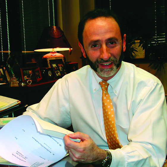 actuarial tools: Shay Bilchik (headshot), smiling man with gray beard and mustache wearing white shirt, yellow polka-dotted tie