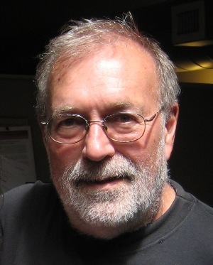 Mike Males (headshot), senior research fellow for the Center on Juvenile and Criminal Justice, serious-looking man with thinning gray hair, beard, mustache, wearing wire-frame glasses, black T-shirt.