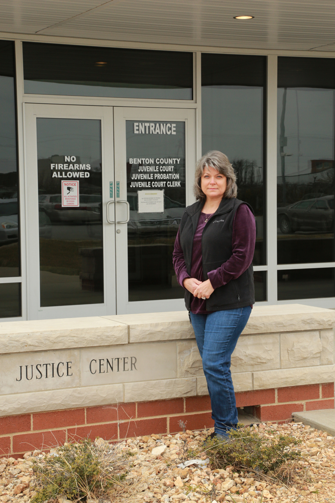 Wendy Jones, wearing purple top, black vest and blue jeans, stands outside entrance to the Benton County Juvenile Court.