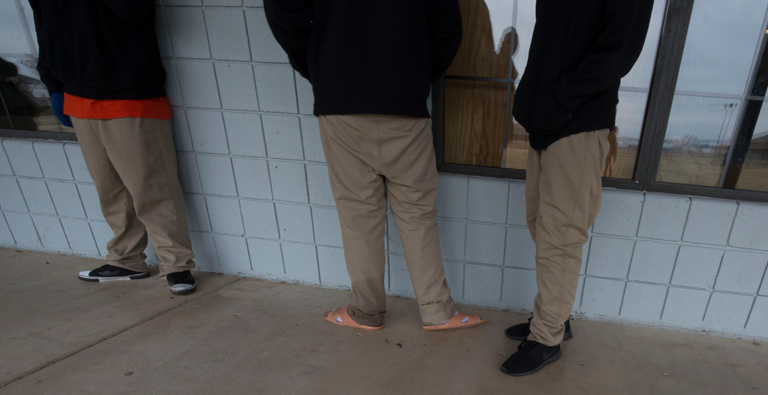 3 people wearing sneakers, slippers in cold outside building.