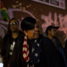 Kimani Gray’s mother in American flag-themed scarf looks to right, looking troubled.
