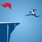 Uncertainty: Businessman jump through the gap obstacles between hill to red flag and success.