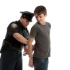 New Zealand: A police officer arrests and handcuffs a young male.