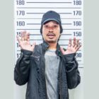 racial and ethnic disparities: Shocked young man in front of police height chart