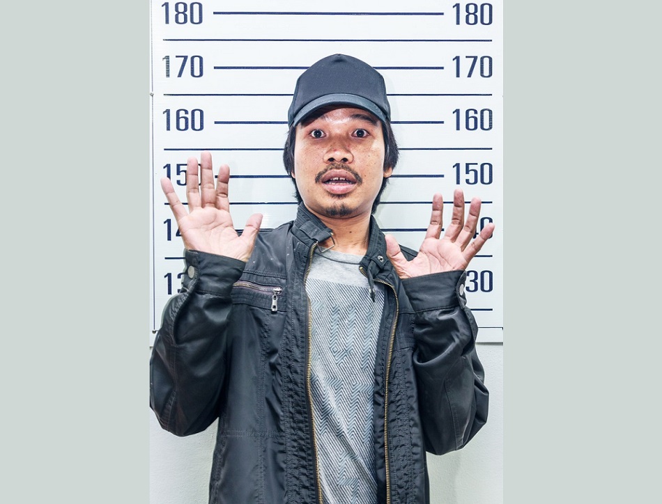 racial and ethnic disparities: Shocked young man in front of police height chart