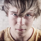 prevention: angry teen with light brown hair over face, mustard yellow shirt
