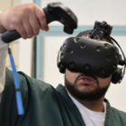 virtual reality: Man with beard, mustache, wearing short-sleeved green top over long-sleeved white top uses virtual reality headset