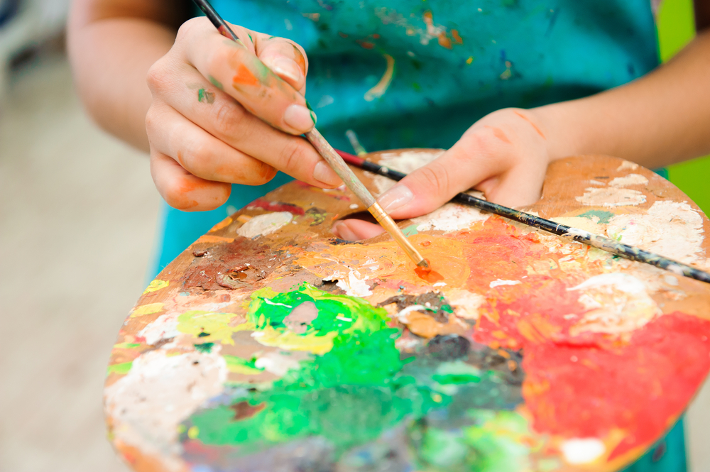 recreational therapy: young girl paints a picture using palette