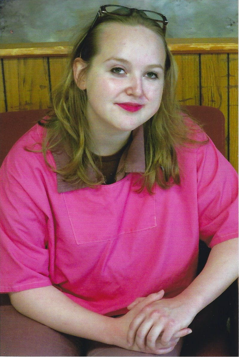 lifers: Jamie Silvonek (headshot), sentenced to 35 years to life in Muncy, Pa., smiling young woman with light brown hair, glasses pushed up on her head, wearing short-sleeved pink uniform over brown collar.