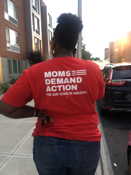 murderversary: Woman wears red T-shirt with logo of Moms Demand Action for Gun Sense in America.