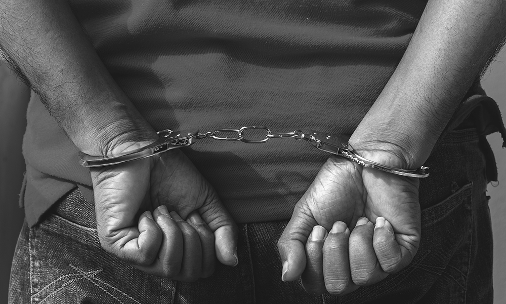 racial and ethnic bias: young person of color with hands handcuffed behind back