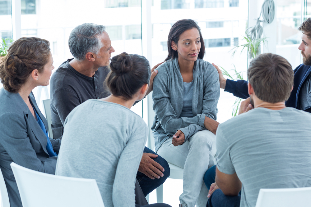 mental health: Concerned people comforting each other at a therapy session
