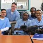 San Quentin: 5 men in light blue sitting or leaning, holding camera equipment.