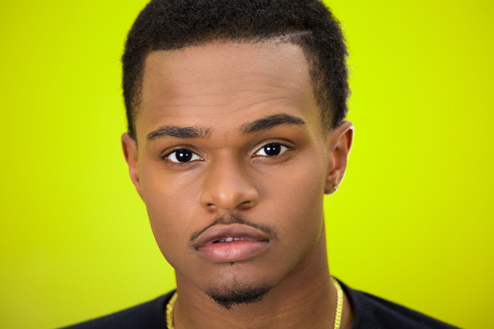 Close-up portrait of serious young man, isolated on green background.