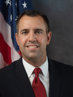 Florida legislature: smiling man in dark suit, white shirt, red tie.