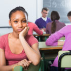 dual system youth: lonely young woman of color sitting away from classmates and feeling depressed