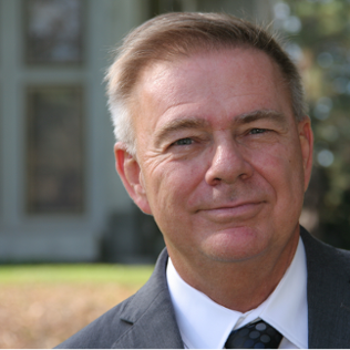 Scott MacDonald (headshot), consultant, smiling man with short white and brown hair, gray suit, white shirt, dark tie.