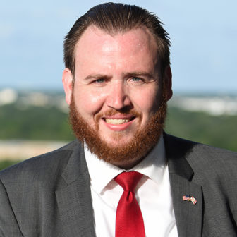 Florida: Smiling man with reddish hair, mustache, beard, gray suit, white shirt, red tie