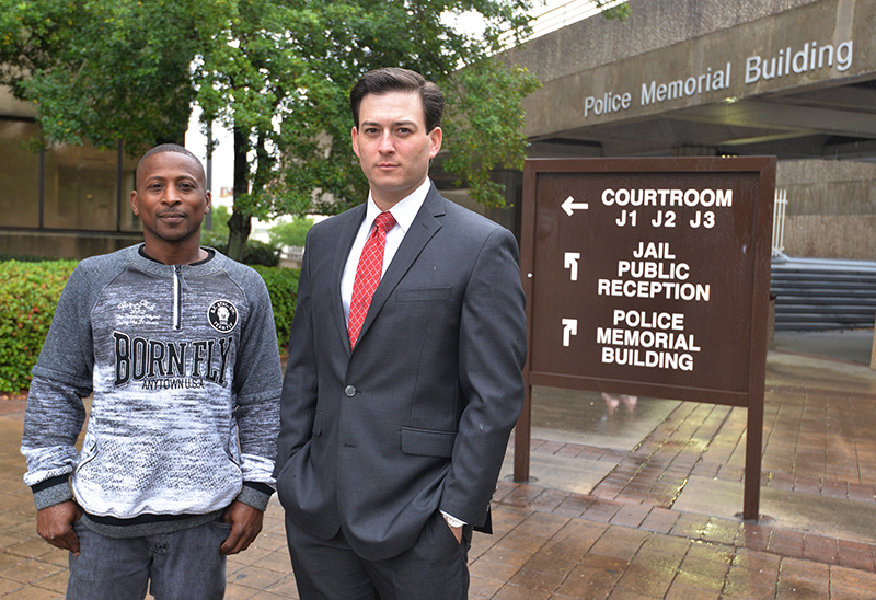 bail: 2 men, one in sweatshirt and jeans, one in suit and tie, stand outside courthouse.