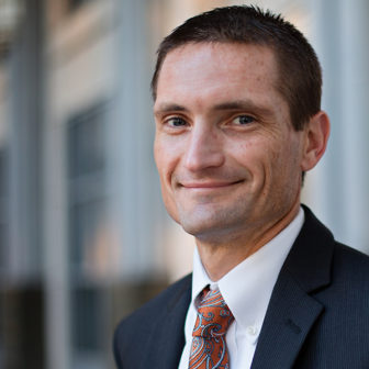 Florida: Smiling man with short dark hair, dark suit, orange paisley tie, white shirt