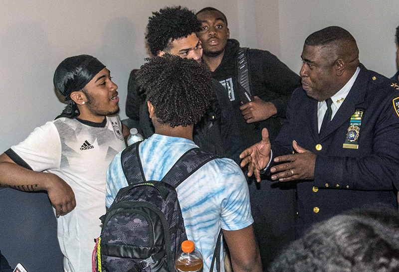 NYPD: Young men of color cluster around police officer of color.