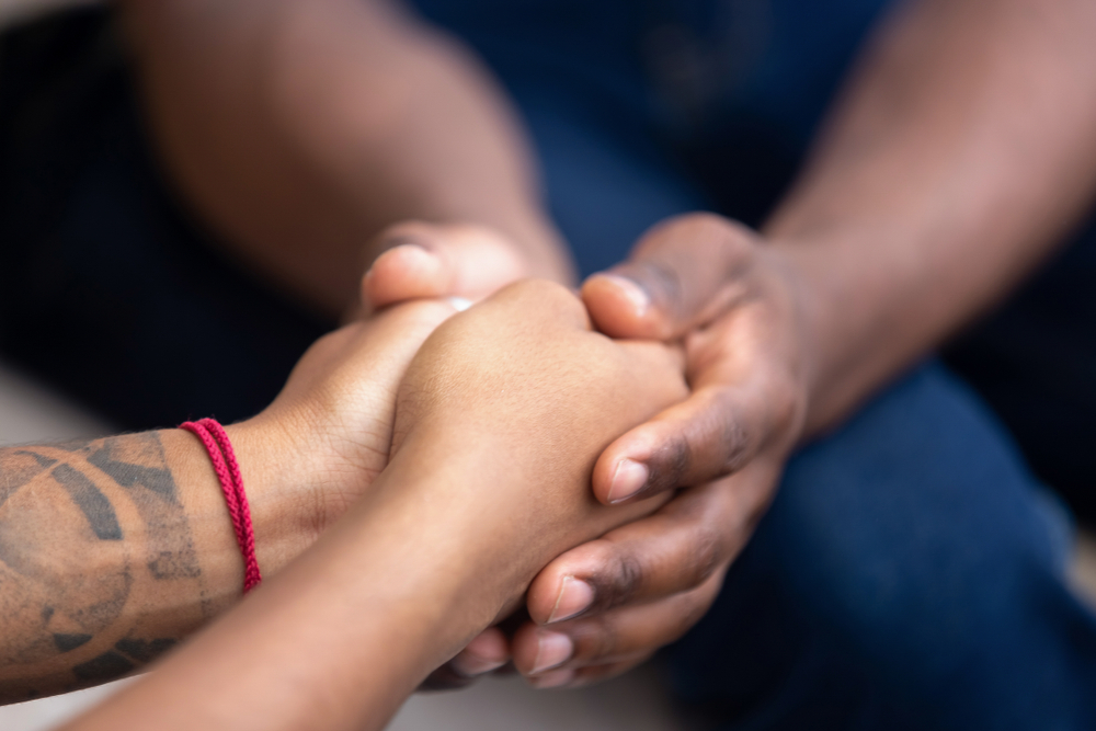 foster home: Black friend holding hands of another black person.