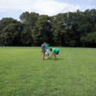 dog training: Distant view of adult, 2 boys in green shirts, tiny dog