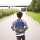 diversion: Boy with backpack facing empty road.