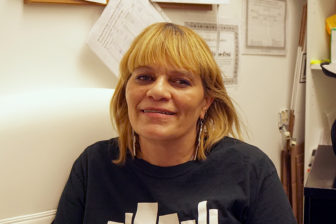 Rikers: Smiling woman with blond hair, long earrings, sweatshirt.