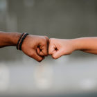whiteness: Close-up of hands of different races doing fist bump.
