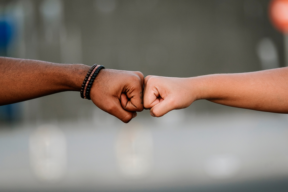 whiteness: Close-up of hands of different races doing fist bump.