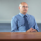 parole: Serious unsmiling balding man sits behind empty desk