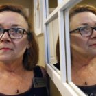 domestic violence: Woman with red hair, glasses, necklace is seen both next to and reflected in mirror at right