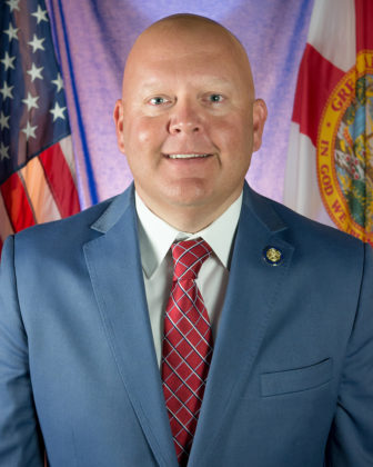 parole: Smiling bald man with blue jacket, white shirt, red patterned tie