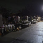 Tessa Majors: Bouquets against railing on wet sidewalk at night