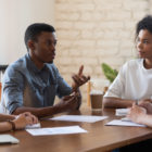 hospital: Man talks to 3 other people around table