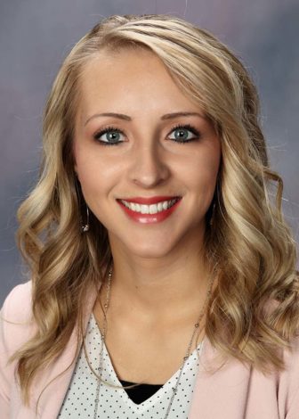 rural: April Terry (headshot), assistant professor at Fort Hays State University, smiling woman with long blonde hair, earrings, necklace, pink blazer, white polka-dotted top