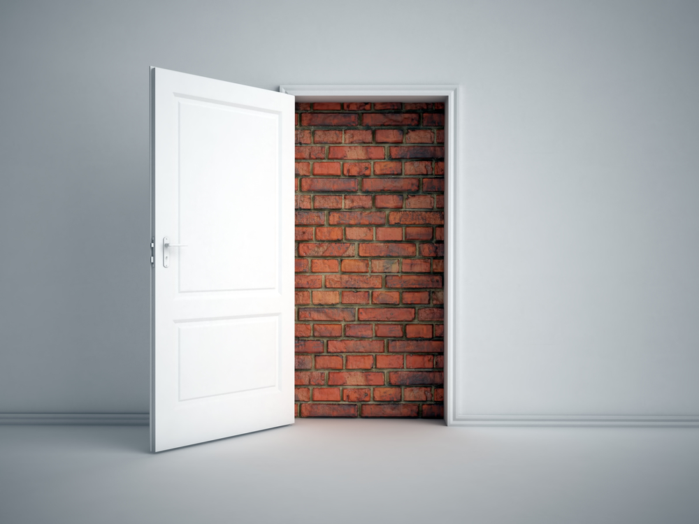 reentry: A brick wall blocking white doorway in white room
