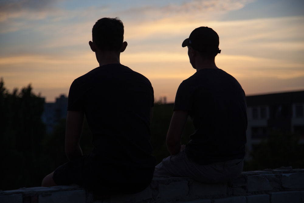 Chicago: silhouette of two friends sitting on the roof at sunset