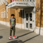 masks: Brick building with address on sign above door; young man on hoverboard on sidewalk