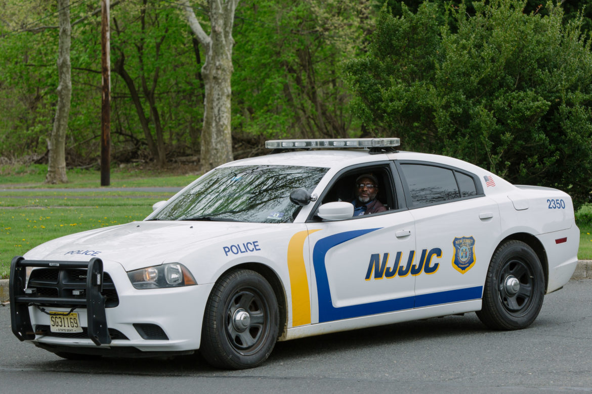solitary: Man in car marked NJJJC looks out the open front left window.
