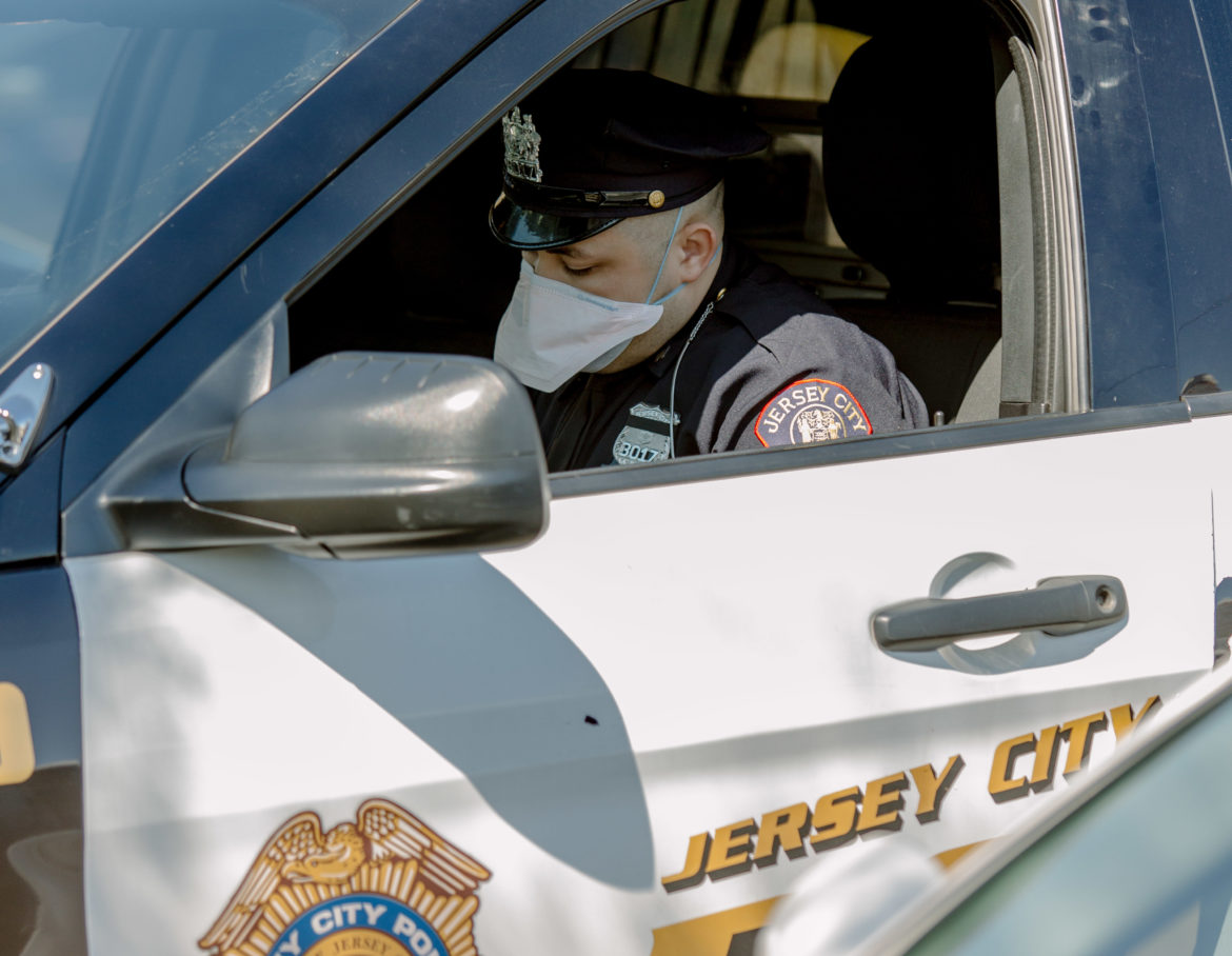 New Jersey: Police officer wearing mask in police car labeled Jersey City.