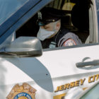 New Jersey: Police officer wearing mask in police car labeled Jersey City.